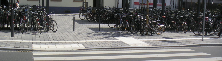 Überweg mit differenzierter Bordhöhe (0 und 6 cm) in Gießen. Ein Leitstreifen führt an den Fahrradständern vorbei.