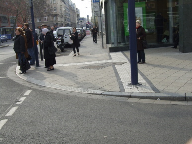 Breite Bordabsenkung für Gehbehindeerte,  Auffindestreifen führen Blinde zum Ampelmast